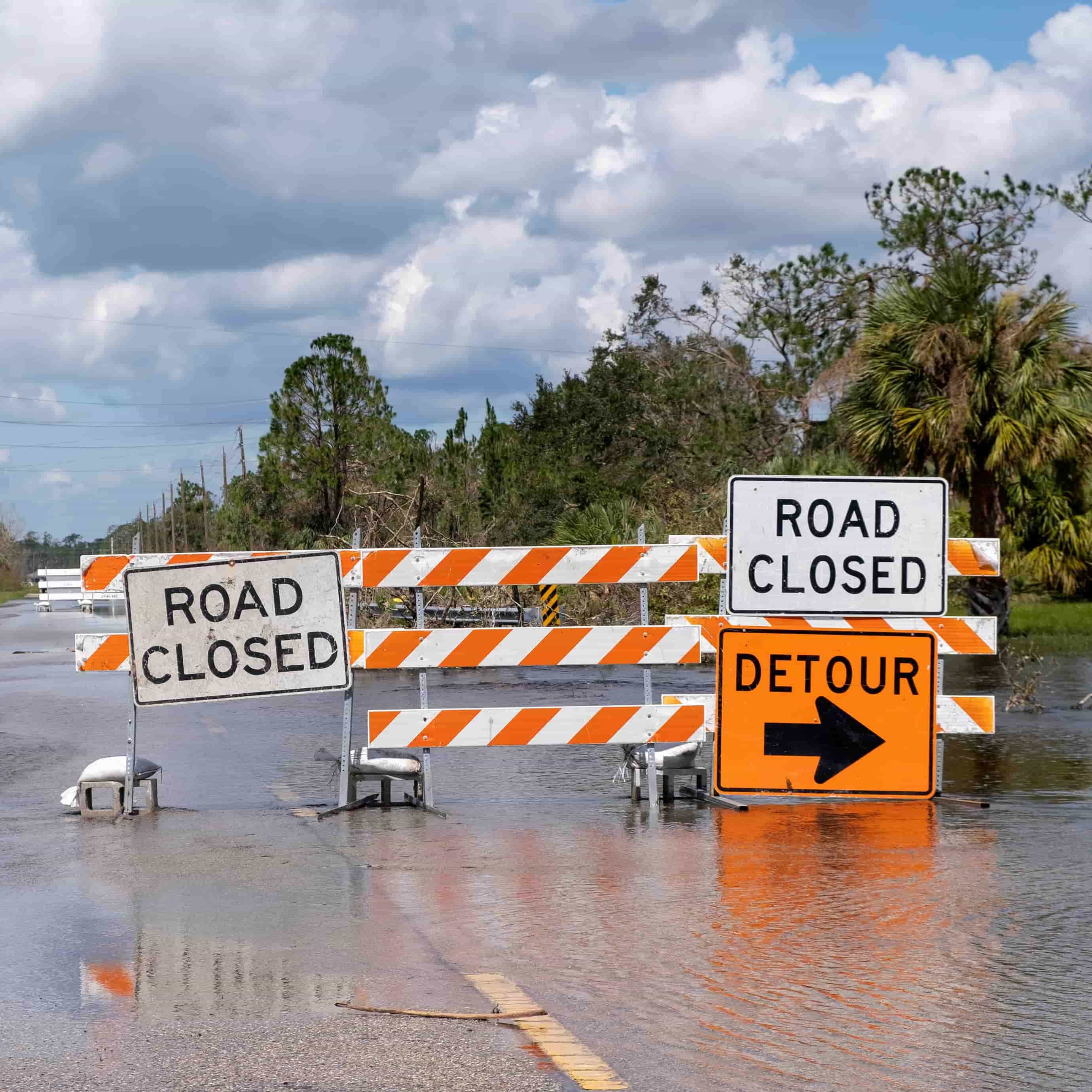 Flooded roadway blocked by road closure barriers highlighting hazardous driving conditions and route disruptions during hurricane season. Flooded roadway blocked by road closure barriers highlighting hazardous driving conditions and route disruptions during hurricane season.