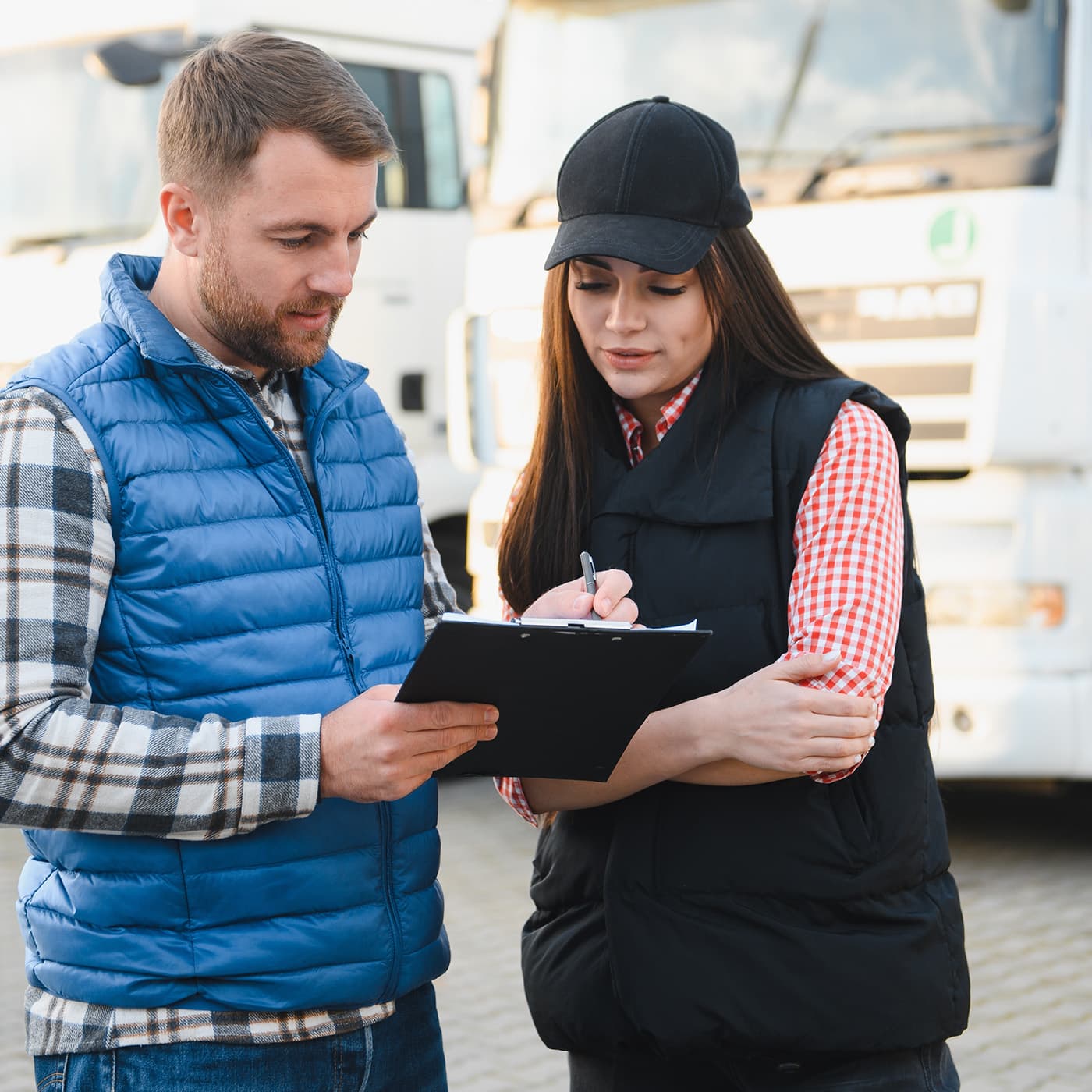 Two fleet professionals reviewing a vehicle inspection checklist to help control maintenance costs and improve fleet efficiency. Two fleet professionals reviewing a vehicle inspection checklist to help control maintenance costs and improve fleet efficiency.