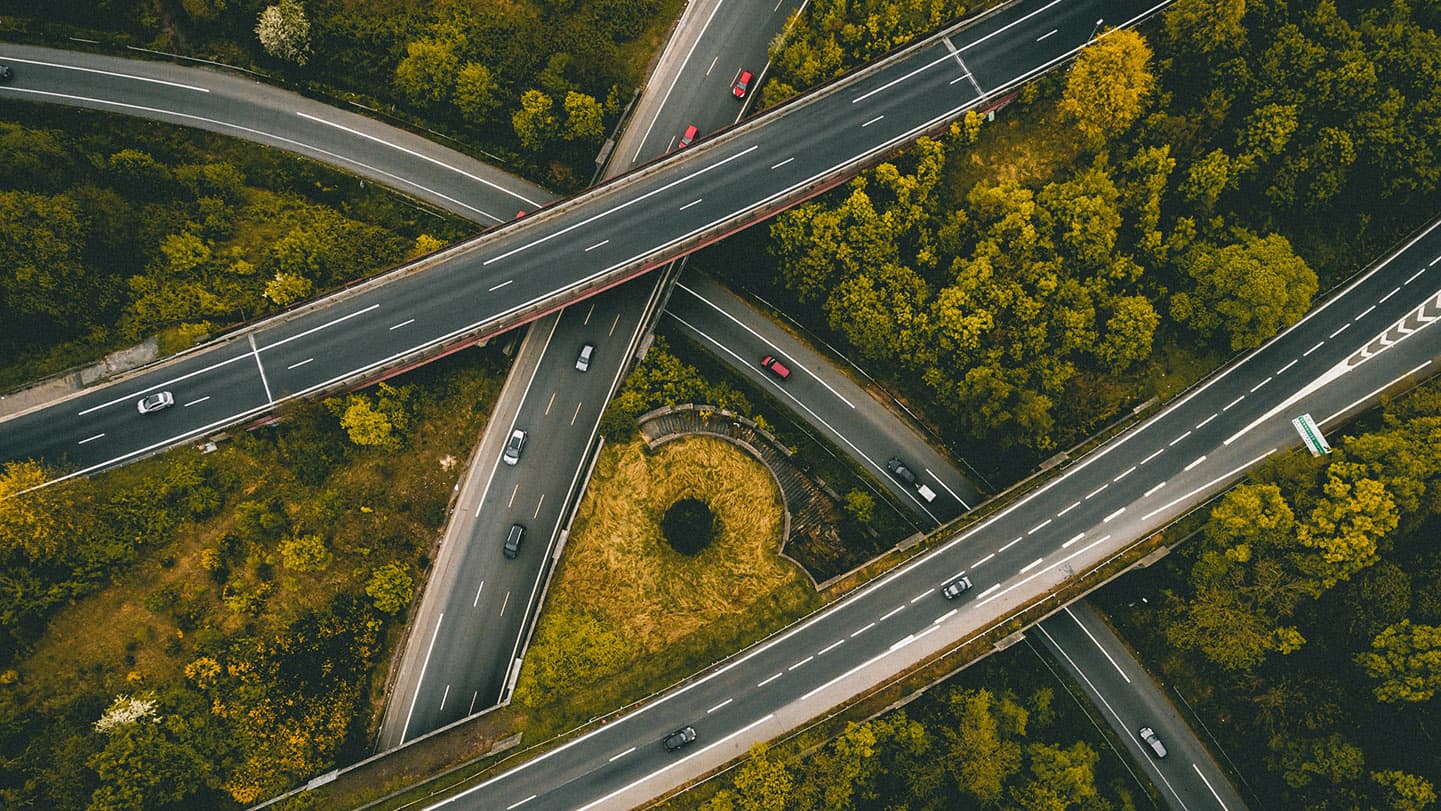 Aerial view of a highway interchange surrounded by dense green forest. Aerial view of a highway interchange surrounded by dense green forest.