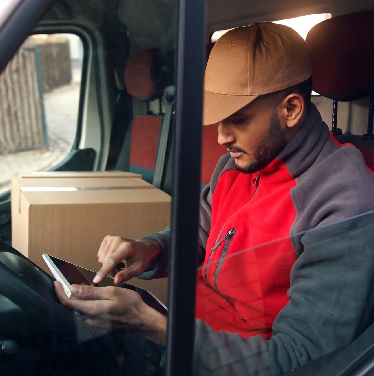 Fleet driver using a tablet while seated in a vehicle, highlighting the importance of safe driving practices and distraction awareness in fleet management. Fleet driver using a tablet while seated in a vehicle, highlighting the importance of safe driving practices and distraction awareness in fleet management.