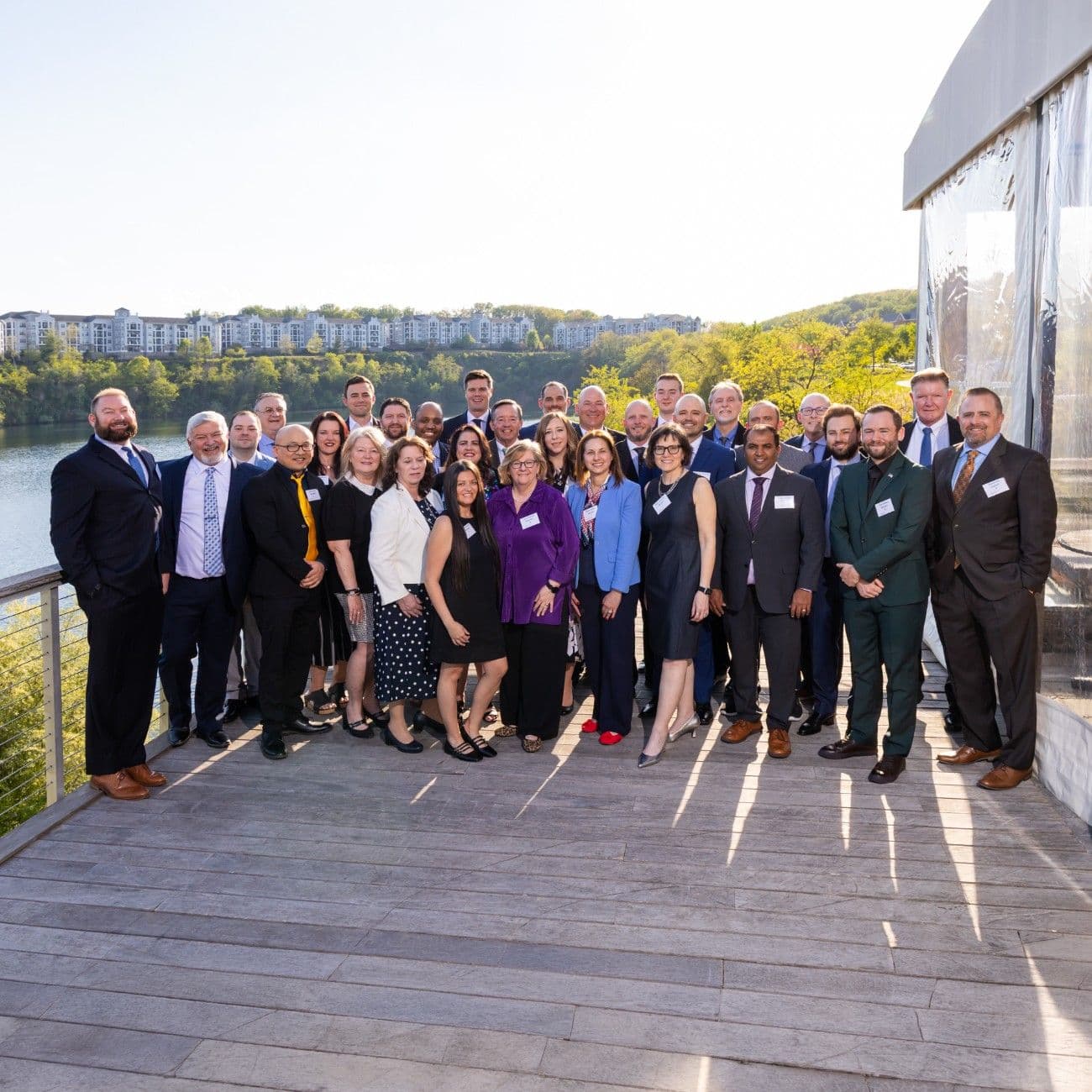 “Group of professionally dressed people posing for a photo at the Element Awards on a riverside deck “Group of professionally dressed people posing for a photo at the Element Awards on a riverside deck