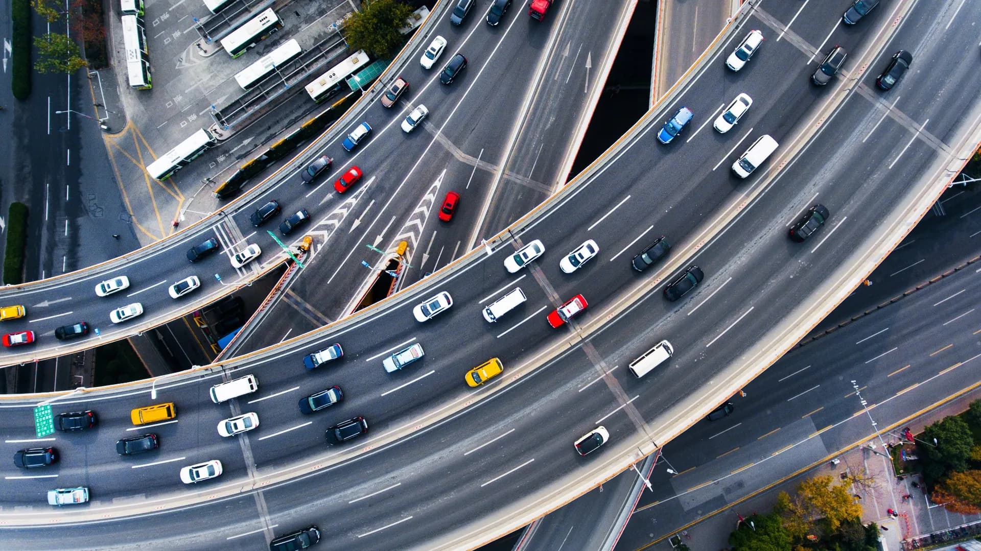 Aerial view of a busy multi-level highway interchange with cars, vans, and buses traveling through an urban area. Aerial view of a busy multi-level highway interchange with cars, vans, and buses traveling through an urban area.