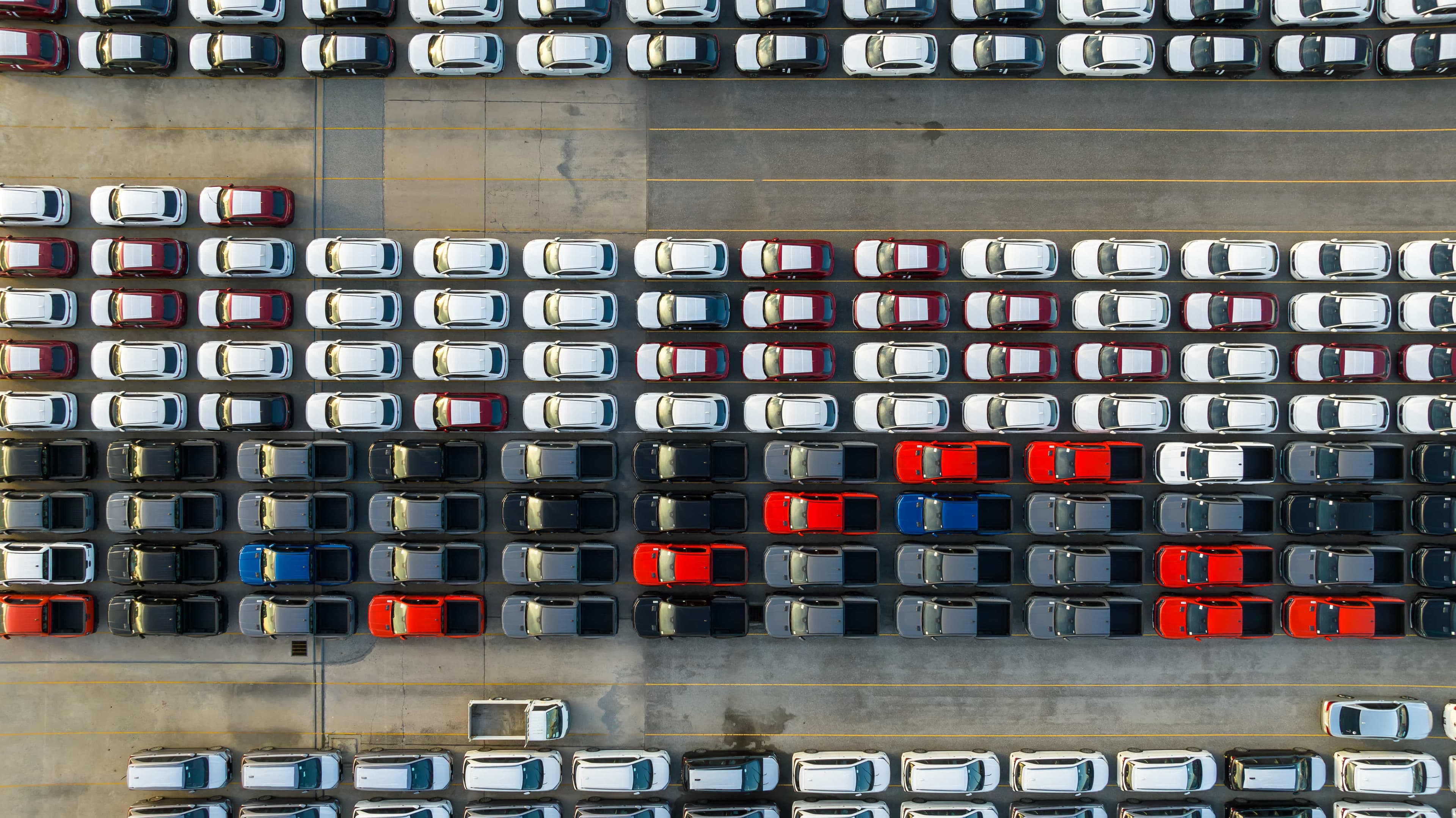 Aerial view of rows of parked cars in a large vehicle storage lot. Aerial view of rows of parked cars in a large vehicle storage lot.