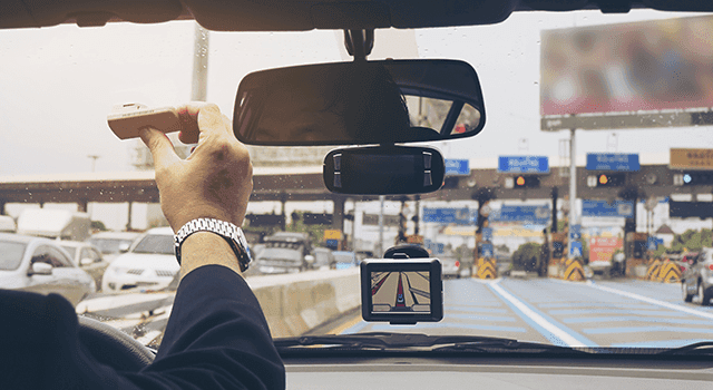 A driver using an in-car GPS navigation device while traveling on a highway. A driver using an in-car GPS navigation device while traveling on a highway.