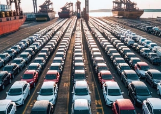 Rows of vehicles sit in lines aboard a large cargo ship.