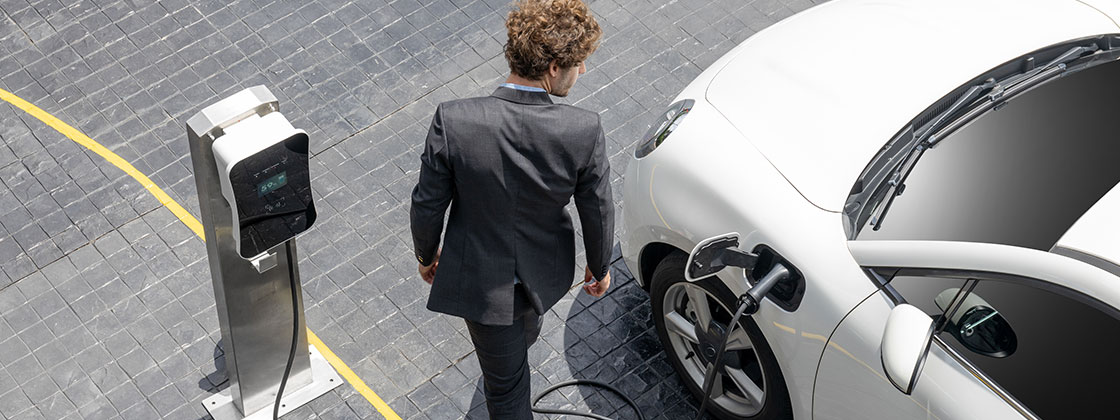 Man in suit walking next to electric car charging
