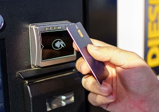 A close up of a fleet employee tapping a fuel card at a gas station to pay for a vehicle fuel refill.
