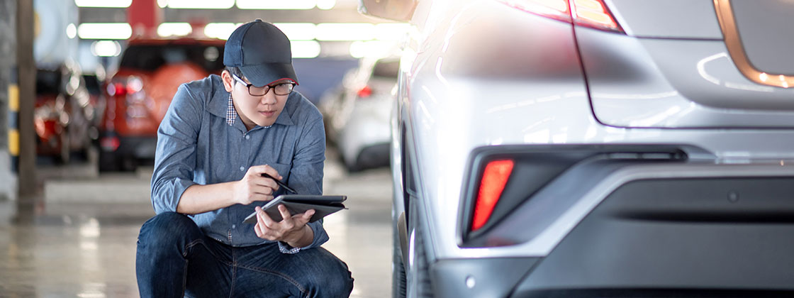 Man kneeling next to car in auto shop