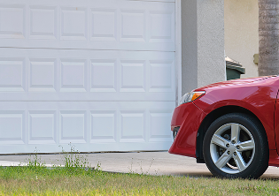 A red company car parked in front of a residential garage door.