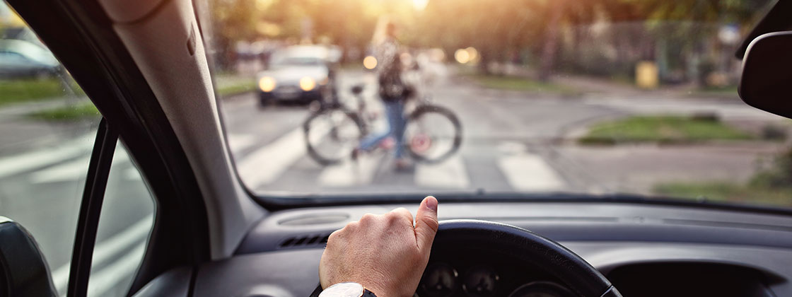 Driver inside car looking at bike rider