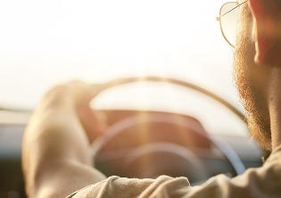 A woman stands beside her car with the hood open as steam rises from the engine block.