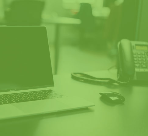 Green shaded image of laptop and phone on desk