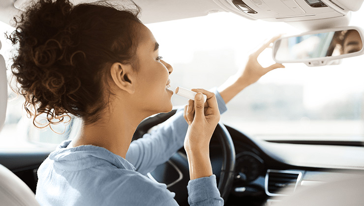 Woman driving and putting on makeup