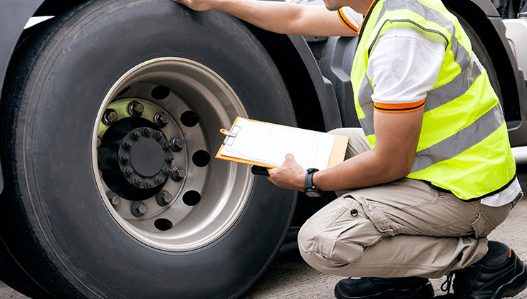 worker inspecting heavy truck tire