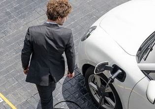 Man in suit walking next to electric car charging