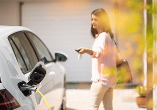 Une femme rechargeant un véhicule électrique à la maison