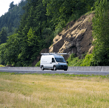 White service van traveling down mountain road