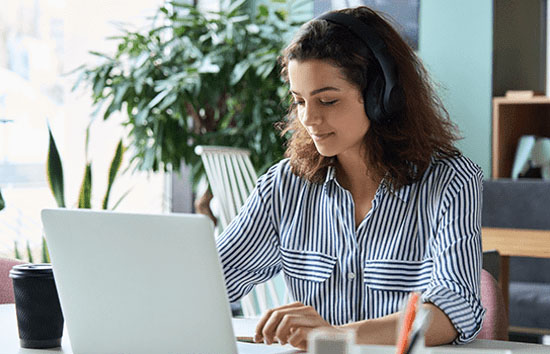 Woman wearing headphones at desk with laptop