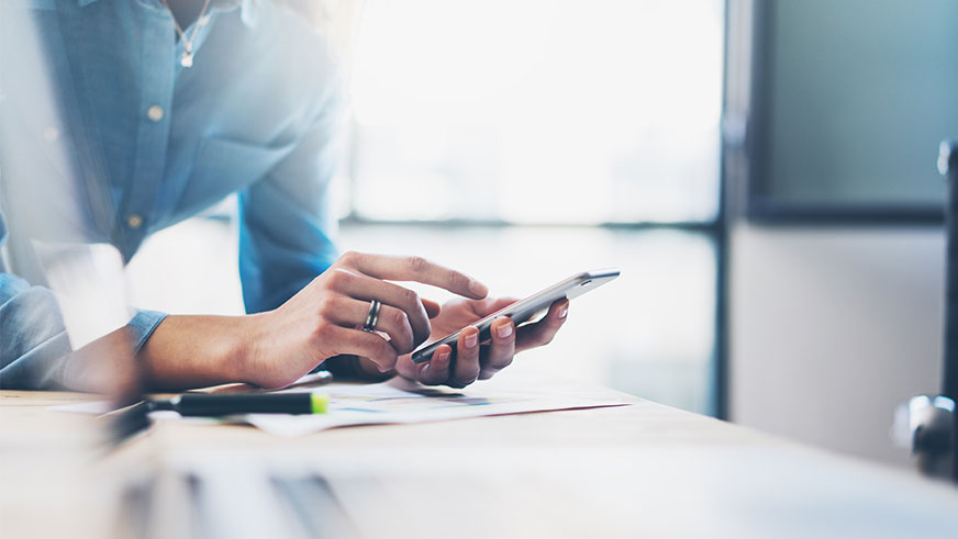 Woman using device and looking at financial documents